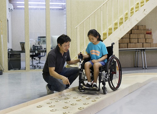 심재신 토도웍스 대표가 토도웍스 사옥에 위치한 휠체어 전용 교육장에서 장애 아동에게 수동휠체어용 전동 키트를 활용한 이동 교육을 진행하고 있다.(사진=SK행복나눔재단 제공)