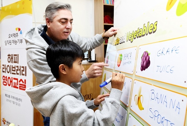 오비맥주 고동우 대표가 해오름 지역아동센터 아동에게 영단어 철자를 가르쳐주고 있다.(사진=오비맥주 제공)