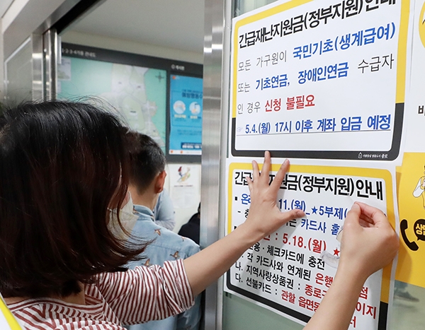 지난 4일 서울 종로구 종로1,2,3,4가동 주민센터에서 관계자가 긴급재난지원금 안내문을 붙이고 있다 (사진= 뉴시스)