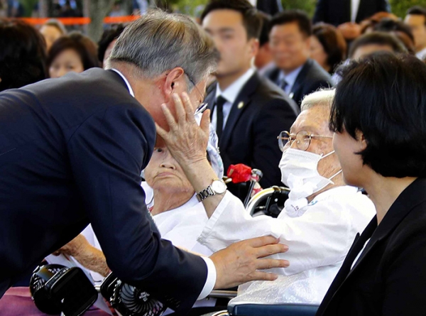 문재인 대통령이 2018년 8월 14일 충남 천안 국립 망향의 동산에서 열린 일본군 위안부 피해자 기림의 날 기념식에 입장하며 김경애 할머니와 인사하자 할머니가 대통령 얼굴을 만져보고 있다. (사진= 뉴시스)